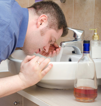 Man with hangover washing up