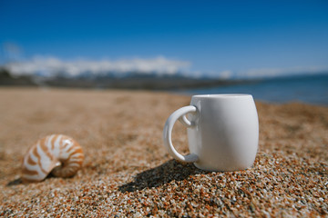 espresso coffee cup  on the issyk-kul beach sand with mountains