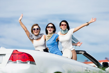 Group of girls stands in the car with hands up