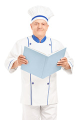 A mature chef holding a cookbook and looking at camera