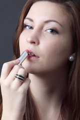 beautiful young woman applying lipstick