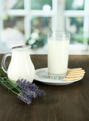 Glass of milk, a jug and cookies on a room background