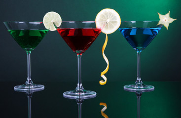 Alcoholic cocktails in martini glasses on dark green background