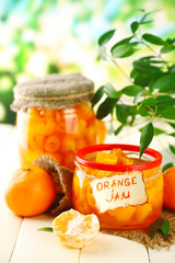 Orange jam with zest and tangerines, on white wooden table