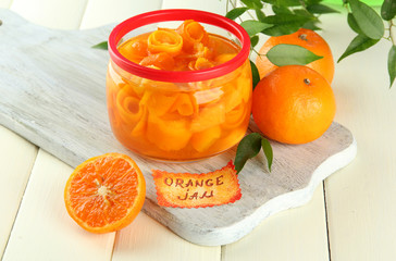 Orange jam with zest and tangerines, on white wooden table