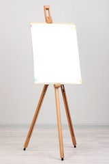 Wooden easel with clean paper in room