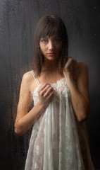 Obraz premium The brunette for a wet glass on a black background.