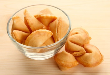 Fortune cookies in bowl, on wooden table
