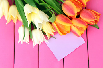 Beautiful white and orange tulips on color wooden background