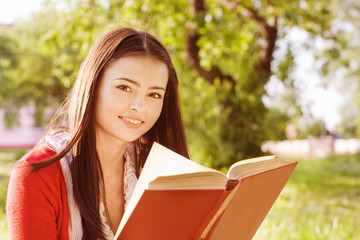 Fototapeta premium beautiful girl reads book in a park