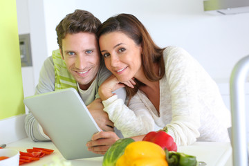 Fototapeta premium Couple in home kitchen looking for lunch recipe