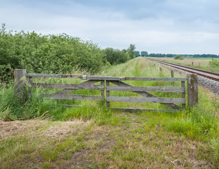 Fototapeta na wymiar Locked wooden gate beside straight railroad tracks