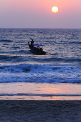 Fishing boat going out towards the setting sun.