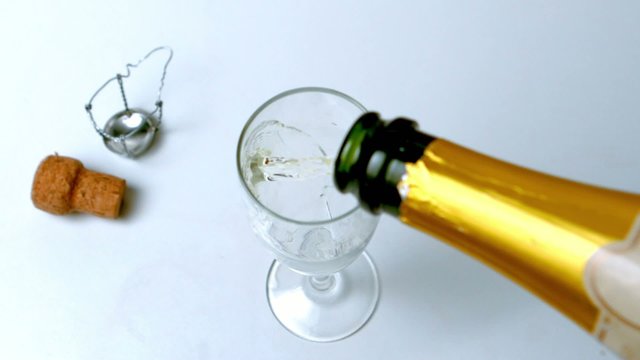 Champagne being poured into flute on white surface
