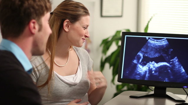 A young couple and a doctor look at an ultrasound.