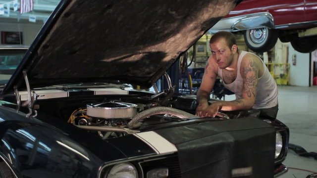 Portrait of a man working on a classic car, dolly shot