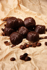 Chocolate candies and coffee beans, on beige paper background