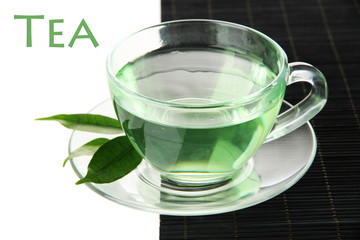 Transparent cup of green tea on bamboo mat, isolated on white