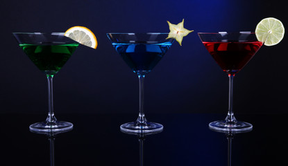 Alcoholic cocktails in martini glasses on dark blue background