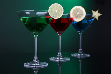 Alcoholic cocktails in martini glasses on dark green background