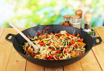 Noodles with vegetables on wok on nature background background