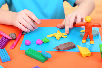 Child moulds from plasticine on table