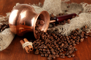 Coffee pot with coffee beans on brown wooden background