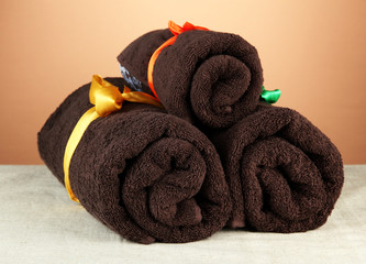 Obraz na płótnie Canvas Three rolled towels, on brown background
