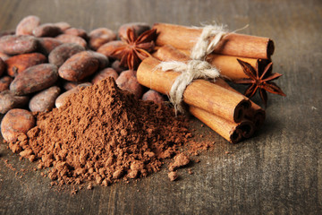 Fototapeta na wymiar Cocoa beans, cocoa powder and spices on wooden background