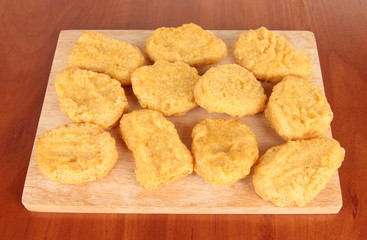 Fried chicken nuggets on cutting board on table