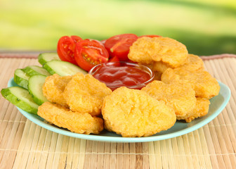 Fried chicken nuggets with vegetables and sauce on table in