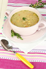 Nourishing soup in pink pan on wooden table close-up