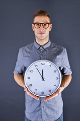 Man holding wall clock over dark background