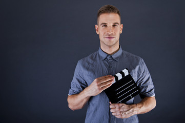 Man with movie clap over dark background