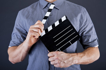 Man with movie clap over dark background