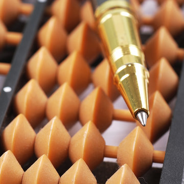 Close-up Of Classic Abacus With Gold Pen