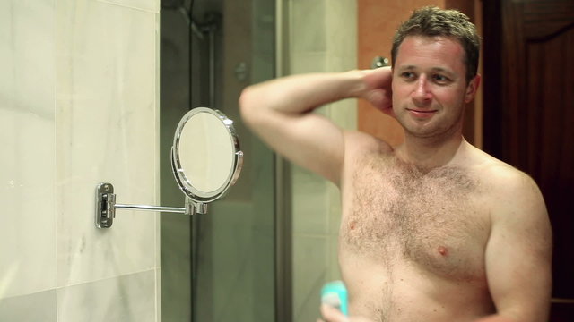 Man takes care of his hygiene by applying deodorant to his  armp
