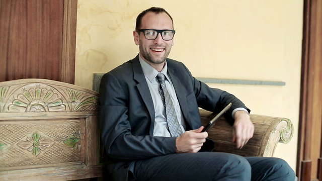 Portrait of happy businessman with tablet sitting on bench in an