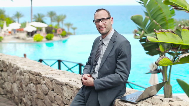 Portrait of smiling businessman using electronics in touristic r