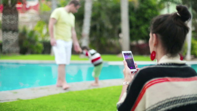 Happy family. Mother taking photo by swimming pool, steadicam