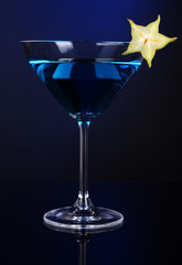 Blue cocktail in martini glass on dark blue background