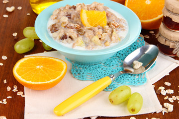 Useful oatmeal in bowl with fruit on wooden table close-up