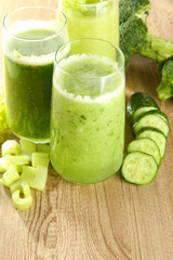 Glasses of green vegetable juice on wooden background