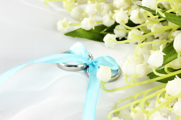 Obraz na płótnie Canvas Wedding rings tied with ribbon on light gentle background
