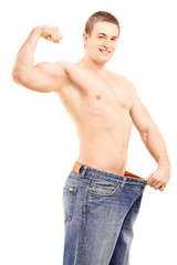 Fototapeta premium Fit muscular man in a big pair of jeans showing his biceps