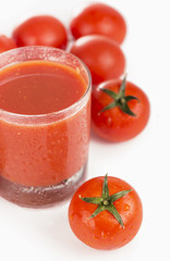 Glass of tomato juice and tomatoes on a white background