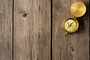 Antique compass over wooden background