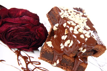 Slices of a brownie on white coverd with chocolate and nuts