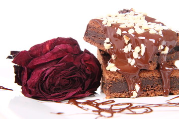Brownie on plate with chocolate and nuts, and a red rose