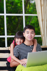 Little asian girl pointing on laptop with big brother